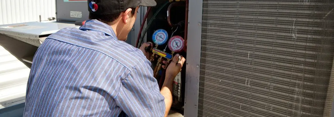 HVAC technician servicing a condenser unit in Augusta